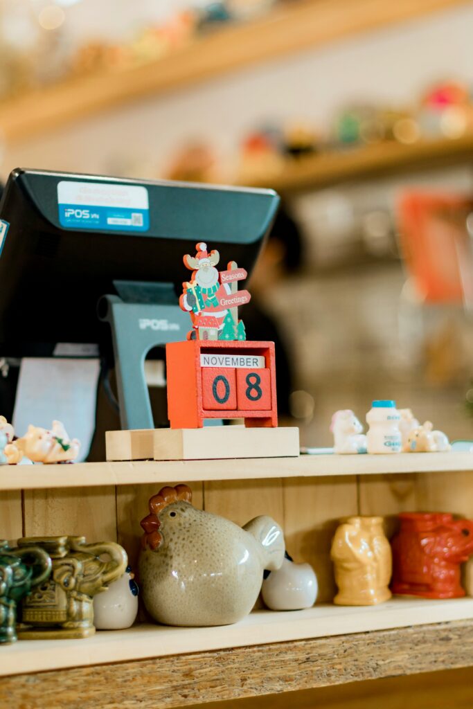 Countertop in a cozy shop featuring a November calendar, collectibles, and a cash register.