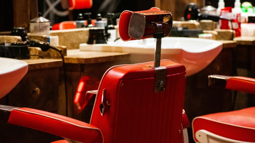 Vibrant red barber chair in an empty modern hair salon with stylish decor and equipment.
